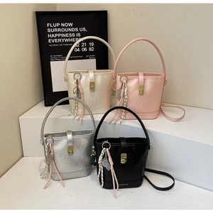 Détail de sacs seaux élégants en quatre couleurs avec fermoirs dorés et pompons