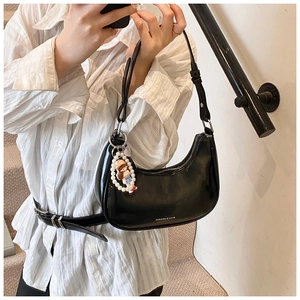 Detail of black crescent shoulder bag with polished finish and decorative pearl charm