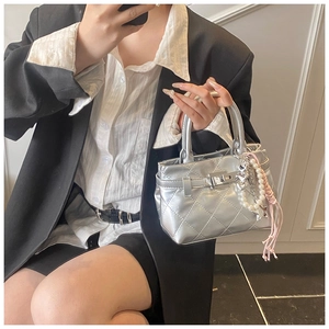 Selfie miroir montrant un petit sac argenté matelassé avec pompon en perles et boucle métal