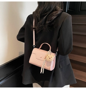 Pink faux leather crossbody bag with teddy bear charm shown on model in black blazer