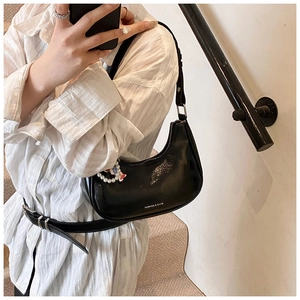 Detail of black glossy hobo bag with pearl charm and fashion print on leather