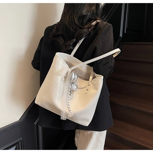 Detail showing white PU leather tote with embossed crown heart patterns and lace ribbon