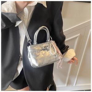 Détail d'un mini sac argenté matelassé avec fermoir métallique et breloque perle