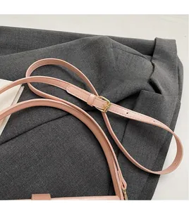 Détail d'une bandoulière réglable en cuir rose clair avec boucle en métal doré
