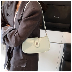 Detail view of mint green crescent shoulder bag with metallic clasp on a dark suit blazer