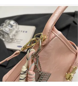 Détail du sac seau rose clair avec ferrures dorées et breloques décoratives de luxe