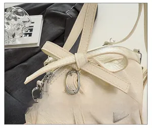 Détail du sac en cuir grainé blanc cassé avec nœud décoratif et fermeture éclair argentée