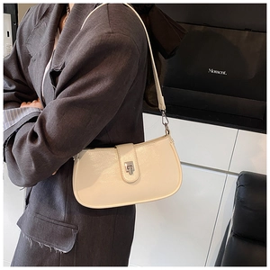 Detail shot of a cream faux leather baguette bag with silver buckle and metal hook