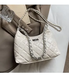 Detail of cream quilted hobo bag with silver chain strap and metal turn-lock closure