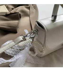 Detail of white leather handbag featuring glossy silver hardware and pearl chain strap