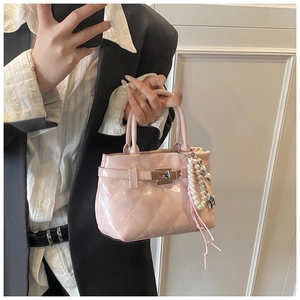 Détail d'un sac à main matelassé rose avec fermoir rotatif et breloque en perles