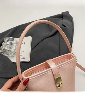 Détail du sac seau rose avec cuir texturé, fermoir doré et poignée de transport