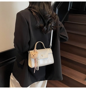 Detail of white PU leather crossbody bag with pearl flap and plush bear charm