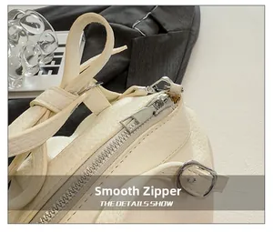 Détail de la fermeture éclair argentée et boucle métallique sur sac en cuir crème