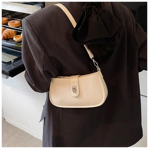 Model wearing a cream half-moon crossbody bag with silver buckle in a lifestyle setting