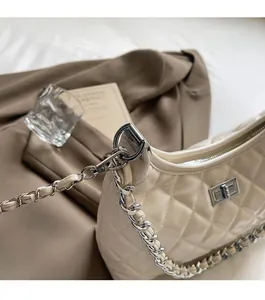 Detailed view of silver turn-lock hardware and quilted texture on creamy white shoulder bag