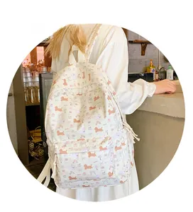 Detail of white backpack with purple and orange cartoon dog patterns worn by model