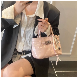 Détail d'un mini sac à main rose clair avec poignée en perles et fermoir argenté