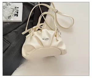 Mini sac à main plissé beige avec plaque métal, taille comparée à un smartphone