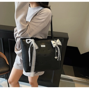 Close-up of black leather tote bag with embossed hearts and lace ribbon detail