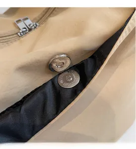 Macro detail of silver magnetic snap button and double zippers on nylon tote bag