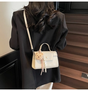 White mini square handbag with pearl accent and teddy charm worn by a model in black