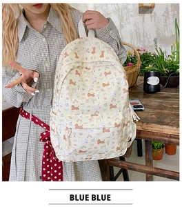 Detail view of cream backpack featuring cute dachshund patterns and pink bow accents