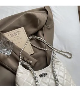Close-up of quilted cream faux leather bag featuring silver metal chain and twist-lock