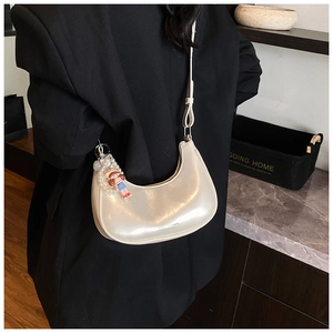 Detail of cream white faux leather hobo bag with pearl cartoon charm on a shoulder strap