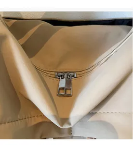 Close-up of the smooth dual metal zippers on a beige nylon commuter tote bag