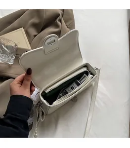 Interior view of white crossbody bag showing storage capacity with a wallet and perfume