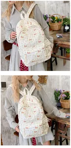 Close-up of cream canvas backpack with cute cartoon dog prints and rustic room background