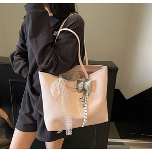 Detail of pink glossy tote bag featuring heart embossing and silver bow pendant