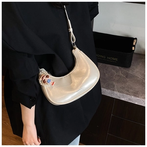 Detail of cream crescent bag with glossy finish and cute pearl doll pendant