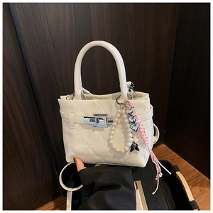 Détail d'un sac matelassé beige avec fermoir argenté et breloque en perles chic