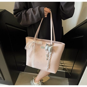 Detail of pink tote bag featuring heart embossing, white lace trim and silver bow charm