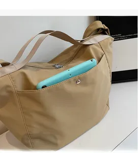 Detail view of khaki nylon tote bag side pocket holding an electronic device
