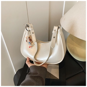 Detail of white pearlescent crescent bag with adjustable strap and pearl doll charm