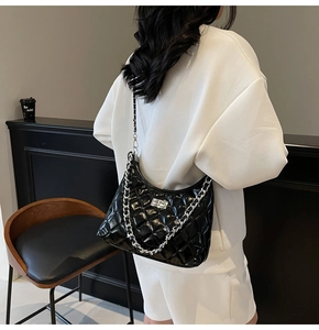 Detail shot of black quilted dumpling bag with silver chain strap and metal clasp
