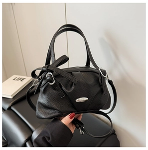 Détail du sac à main en cuir grainé noir avec boucle argentée et décoration de nœud