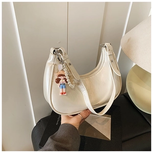 Detail of cream hobo bag with glossy finish and cartoon pearl charm accessory