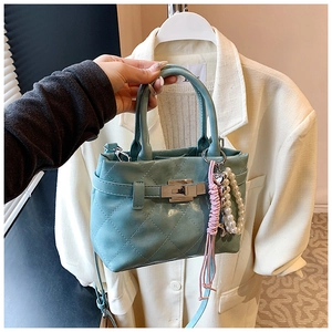 Détail d'un sac à main bleu clair matelassé avec fermoir argenté et perle décorative