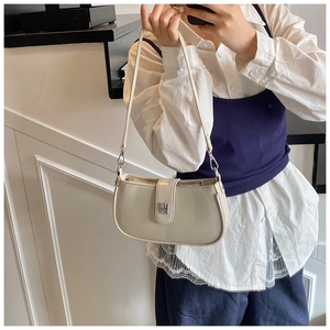 Minimalist beige PU leather hobo bag with silver buckle worn by a model in a modern room