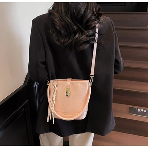 Détail du sac seau rose avec texture cuir, pompon et fermoir métallique doré