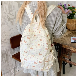 Detail view of cartoon puppy print backpack worn by a model in a cozy indoor setting