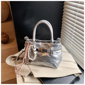 Détail du sac argenté matelassé avec fermoir métallique et breloque étoile sur blazer beige