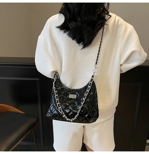 Close-up of black quilted dumpling bag featuring silver chain strap and metal lock