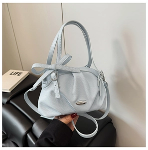 Détail du sac à main plissé bleu clair avec ornement ovale en métal et nœud décoratif