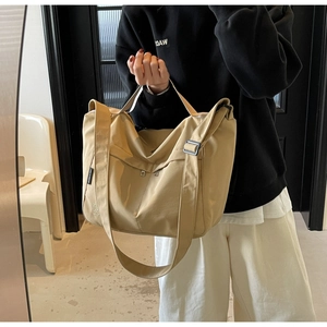 Detail of khaki canvas tote bag with adjustable strap and cat embroidery on the front