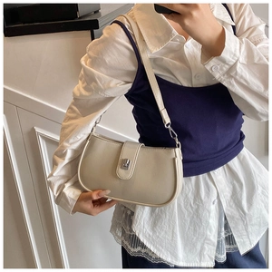 Off-white faux leather baguette bag with silver buckle worn on shoulder by model